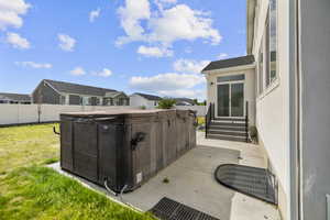 Spacious concrete patio featuring a hot tub/swim spa and direct access to the interior via sliding glass doors