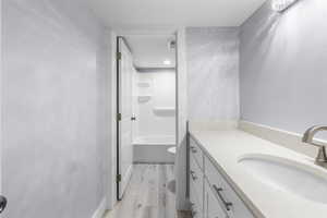 Bathroom vanity with light-toned countertop, undermount sink, and brushed nickel faucet
