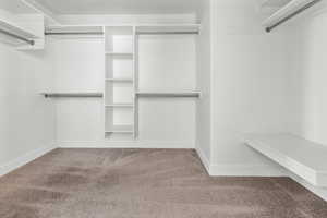 Primary Bedroom closet. Spacious walk-in closet featuring built-in shelving, multiple hanging rods, and a floating storage bench