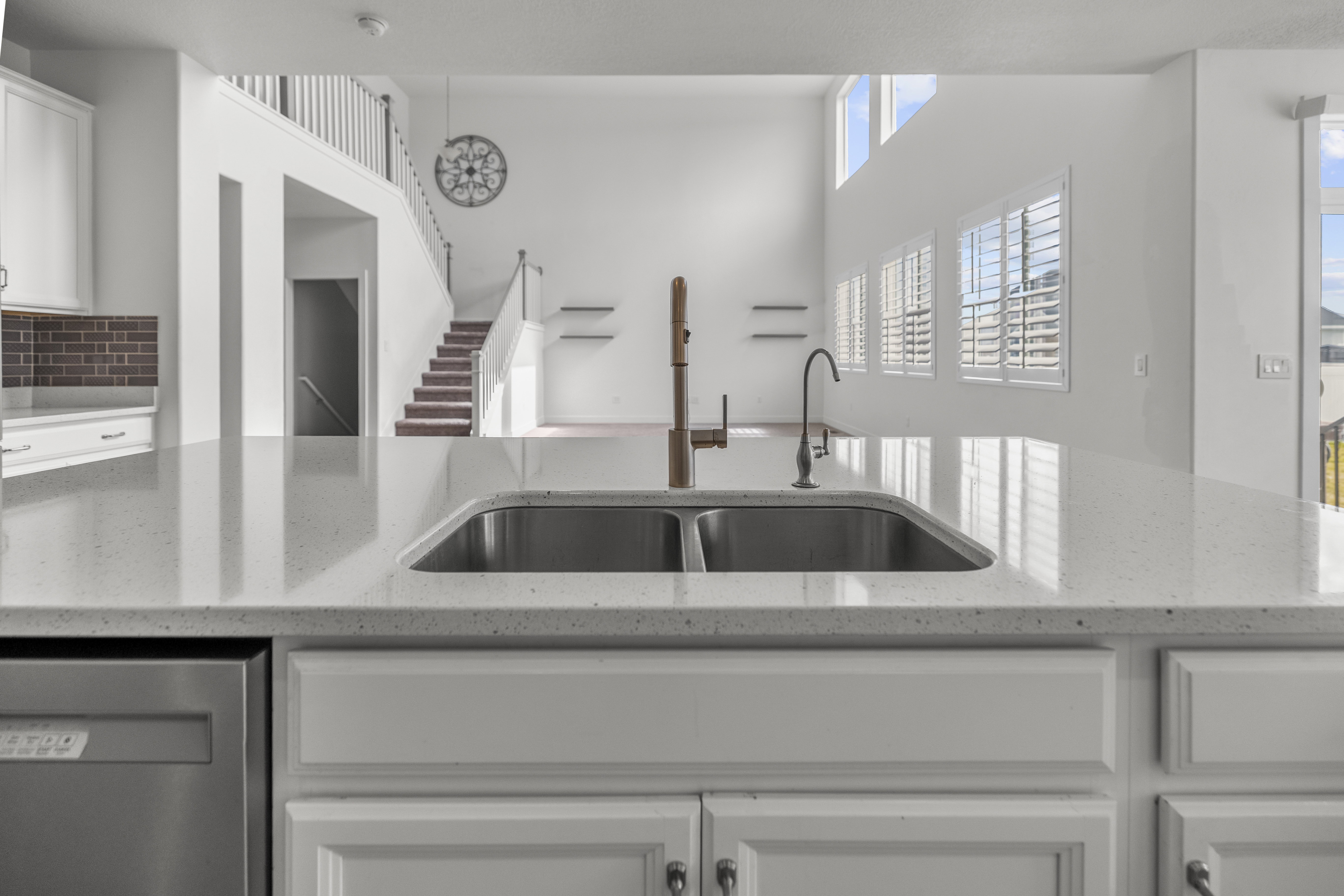 Kitchen island featuring a dual-basin stainless steel sink, two distinct faucets, and a light-toned countertop
