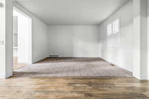 Spacious interior room featuring light-toned carpeting and wood-finish flooring