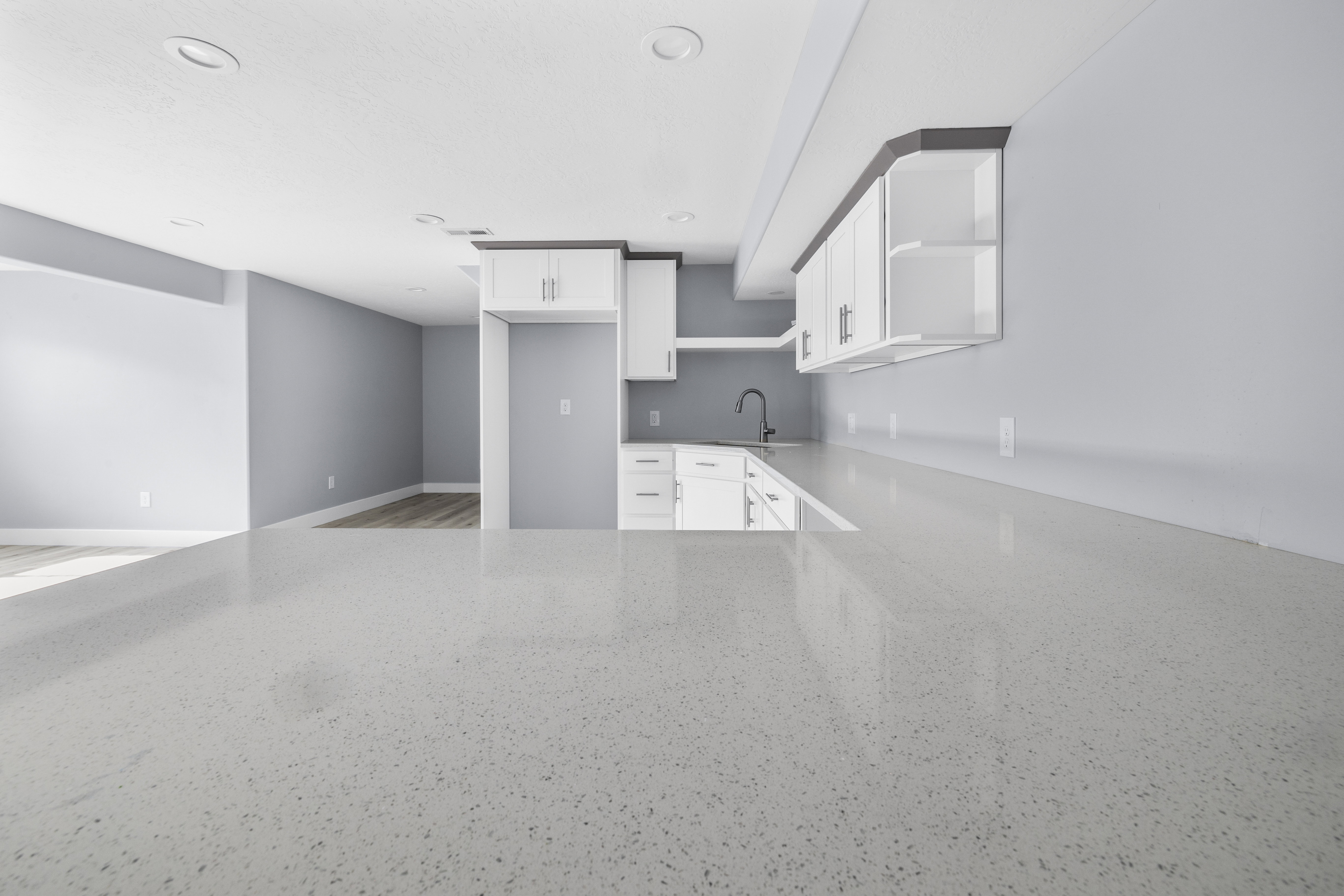 Expansive kitchen island with a light-toned countertop, complemented by white cabinetry and a built-in sink with a gooseneck faucet