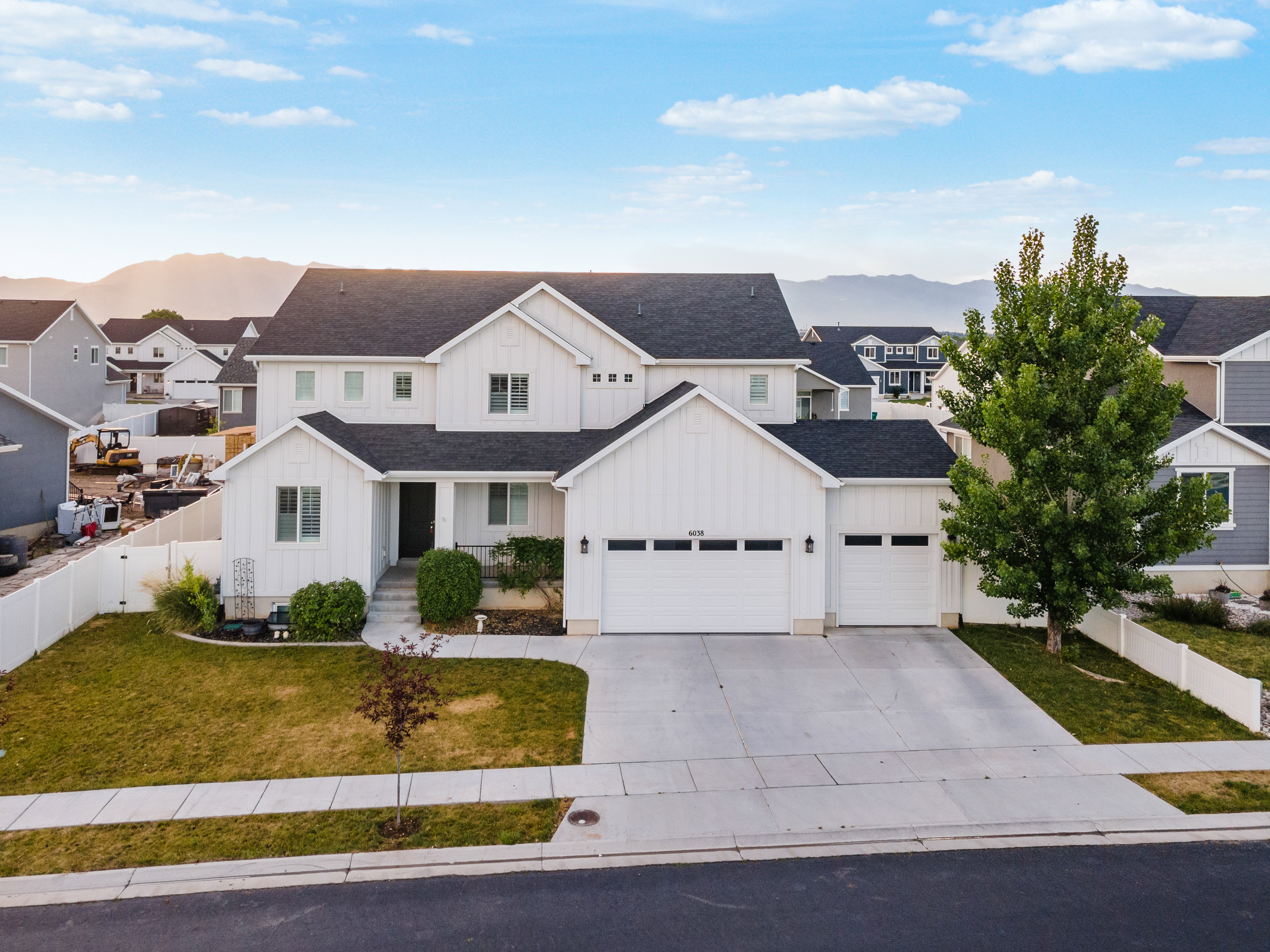Contemporary white exterior with dark roofline, two-car garage, concrete driveway, and front lawn