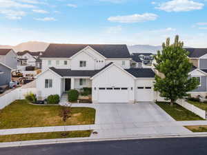 Contemporary white exterior with dark roofline, two-car garage, concrete driveway, and front lawn