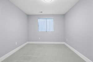 Spacious bedroom featuring neutral paint, light gray patterned carpeting, a single window, and a flush-mount ceiling light