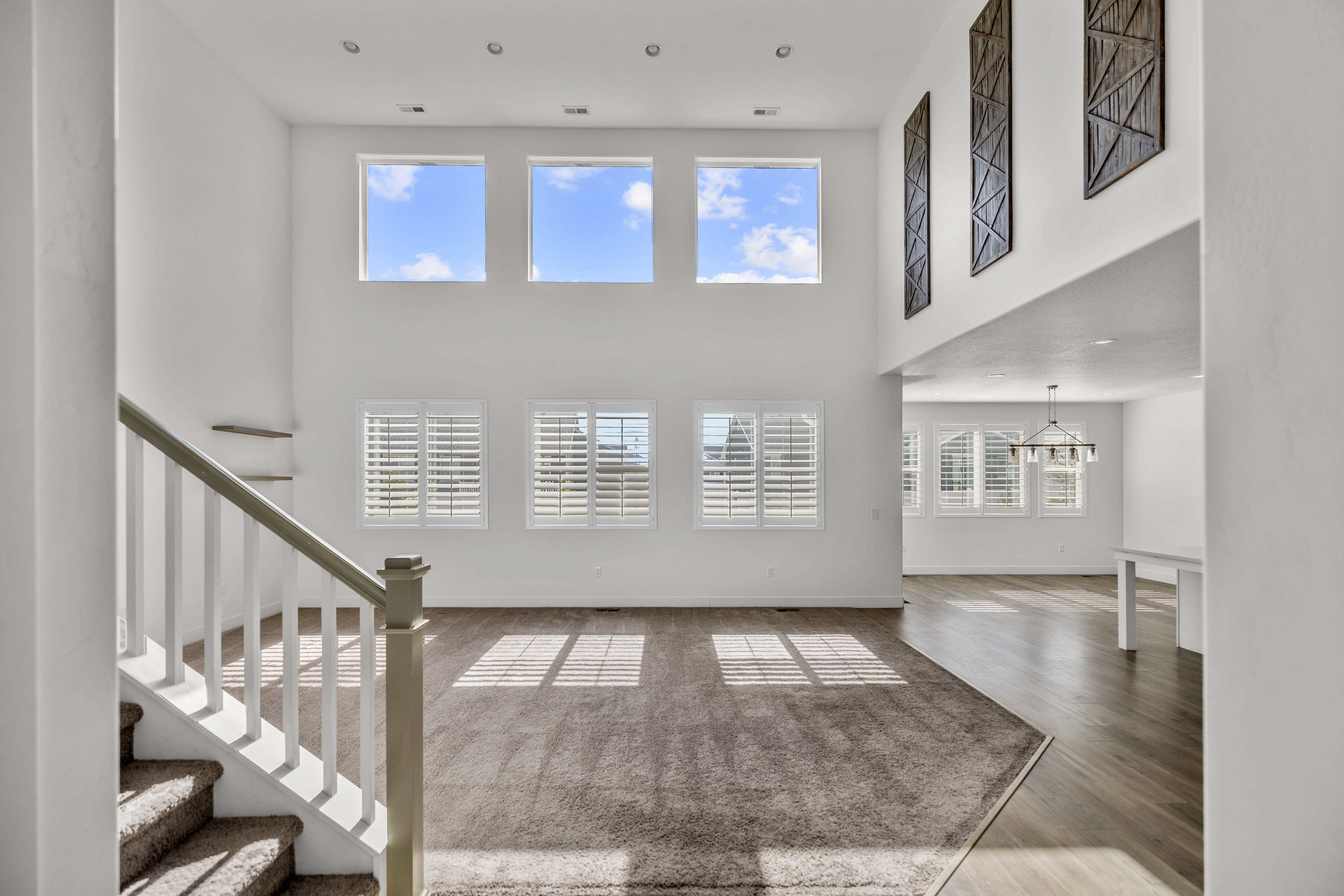 Two-story living area featuring high ceilings, upper-level windows, recessed lighting, and a neutral color palette