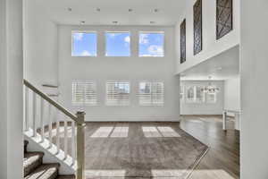 Two-story living area featuring high ceilings, upper-level windows, recessed lighting, and a neutral color palette