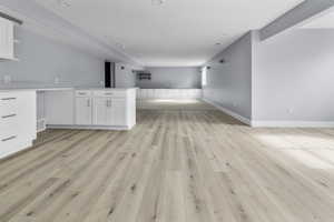 Spacious basement featuring a kitchen and family room with wood-finish flooring, light gray walls, recessed lighting, and white baseboards