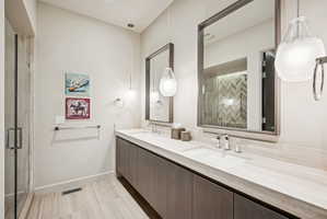 Full bathroom featuring double vanity and a stall shower