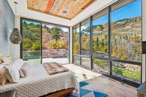 Bedroom featuring floor to ceiling windows, a wood tray ceiling, wood finished floors, and recessed lighting