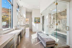 Bathroom with stone tile flooring, vanity, a marble finish shower, recessed lighting, and a high ceiling
