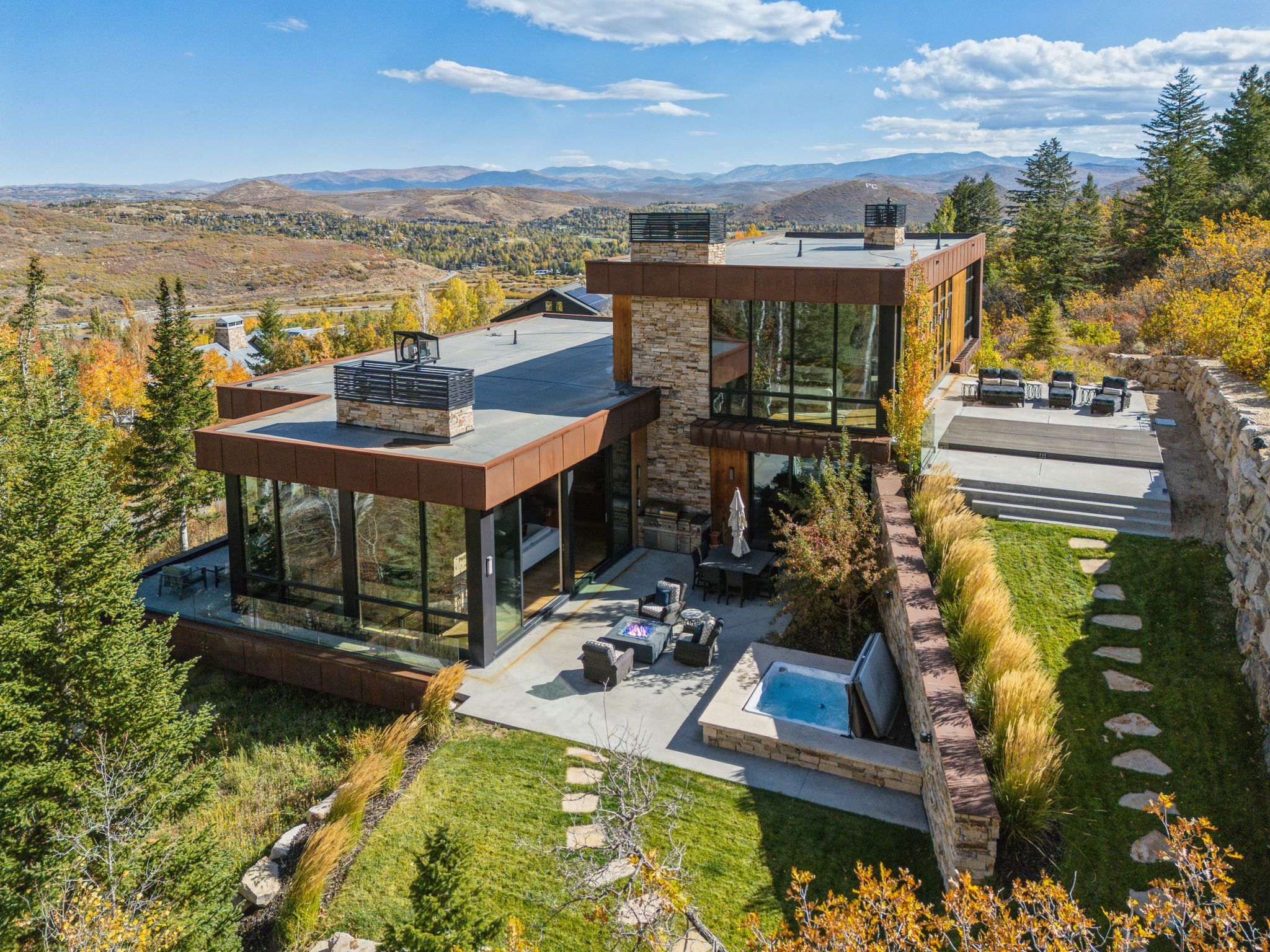 Rear view of house featuring a chimney, a mountain view, a hot tub, and a patio area