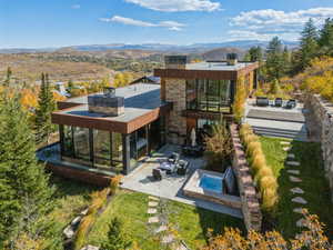 Rear view of house featuring a chimney, a mountain view, a hot tub, and a patio area