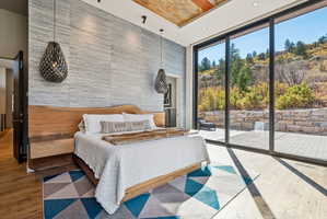 Bedroom featuring expansive windows, wood finished floors, and access to exterior