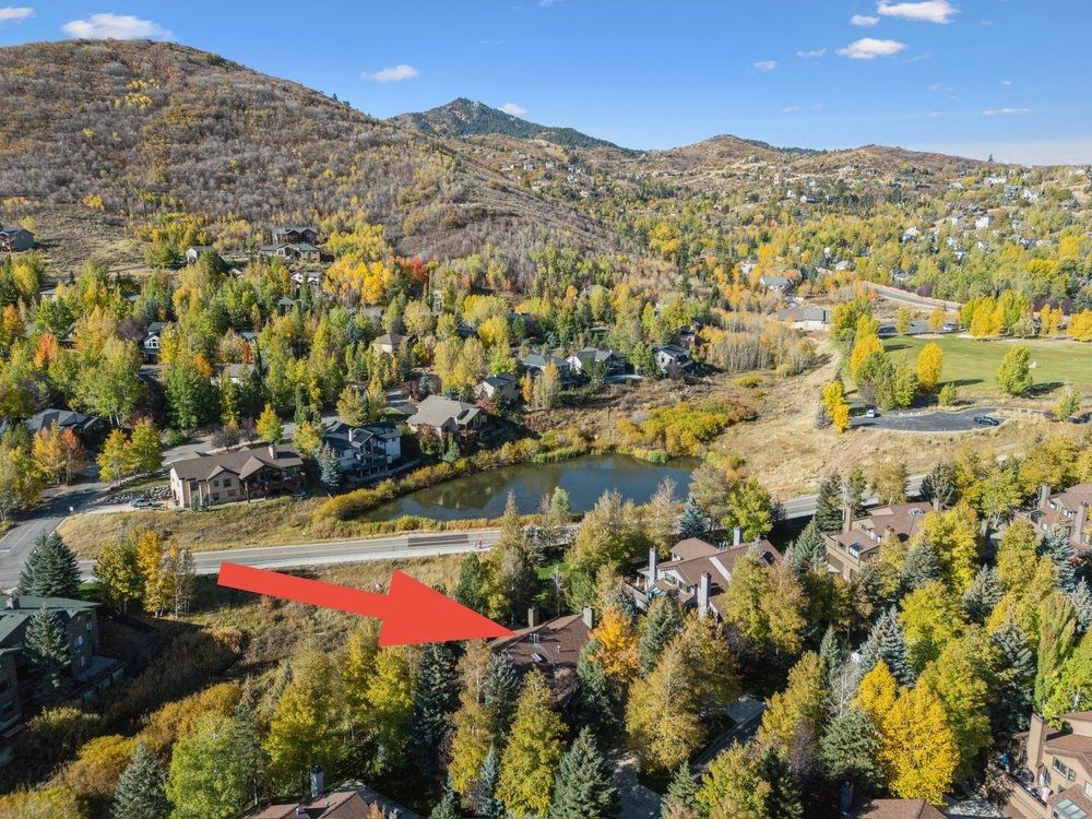 Mountainous landscape with a residential community, featuring a pond and varied autumn foliage