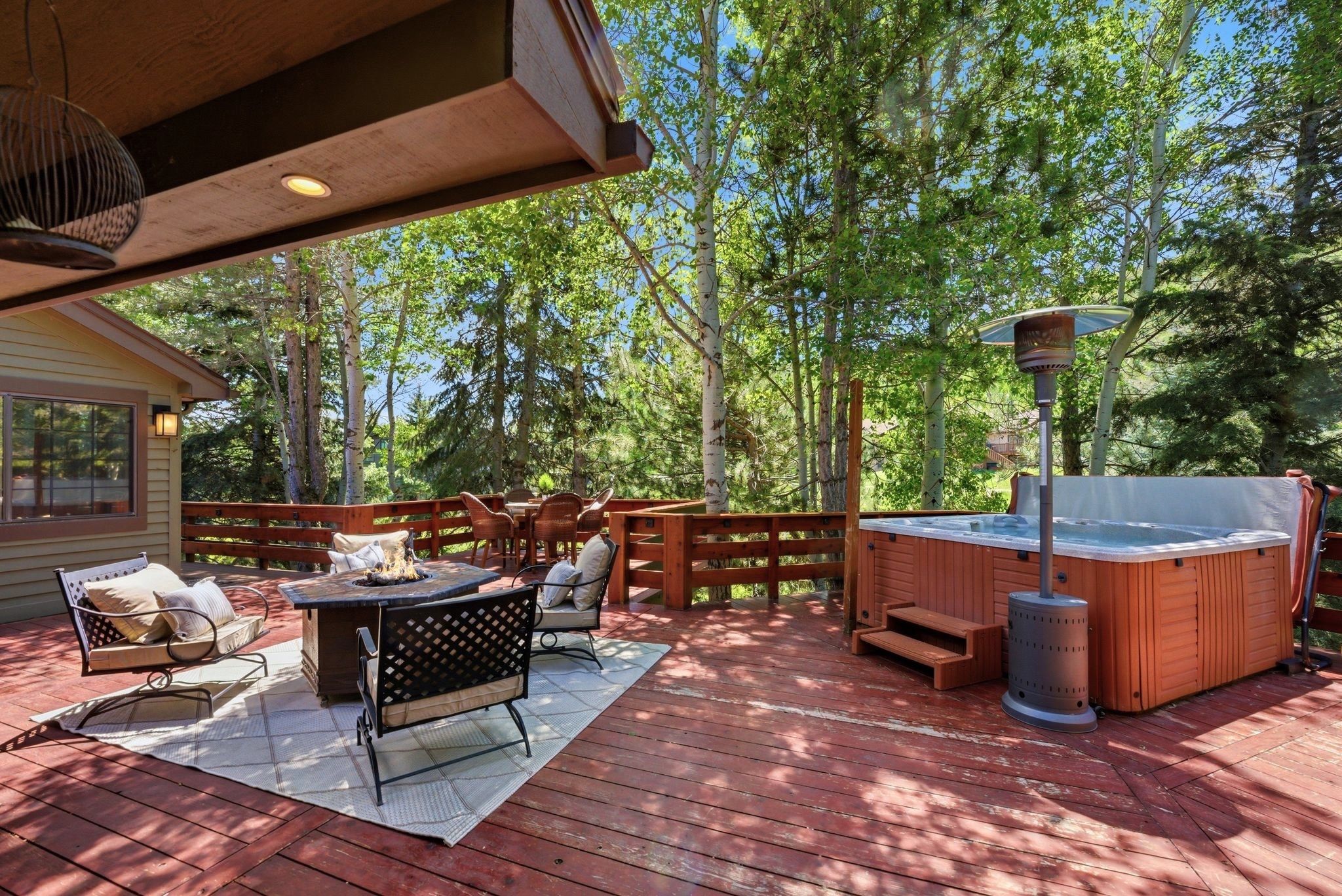 Expansive outdoor deck featuring a built-in hot tub with steps, a dedicated fire pit area, and a separate dining space