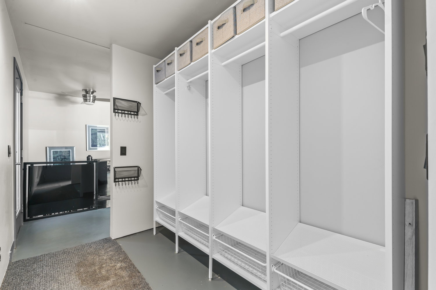 Built-in white storage system featuring multiple compartments, hanging rods, and wire basket drawers