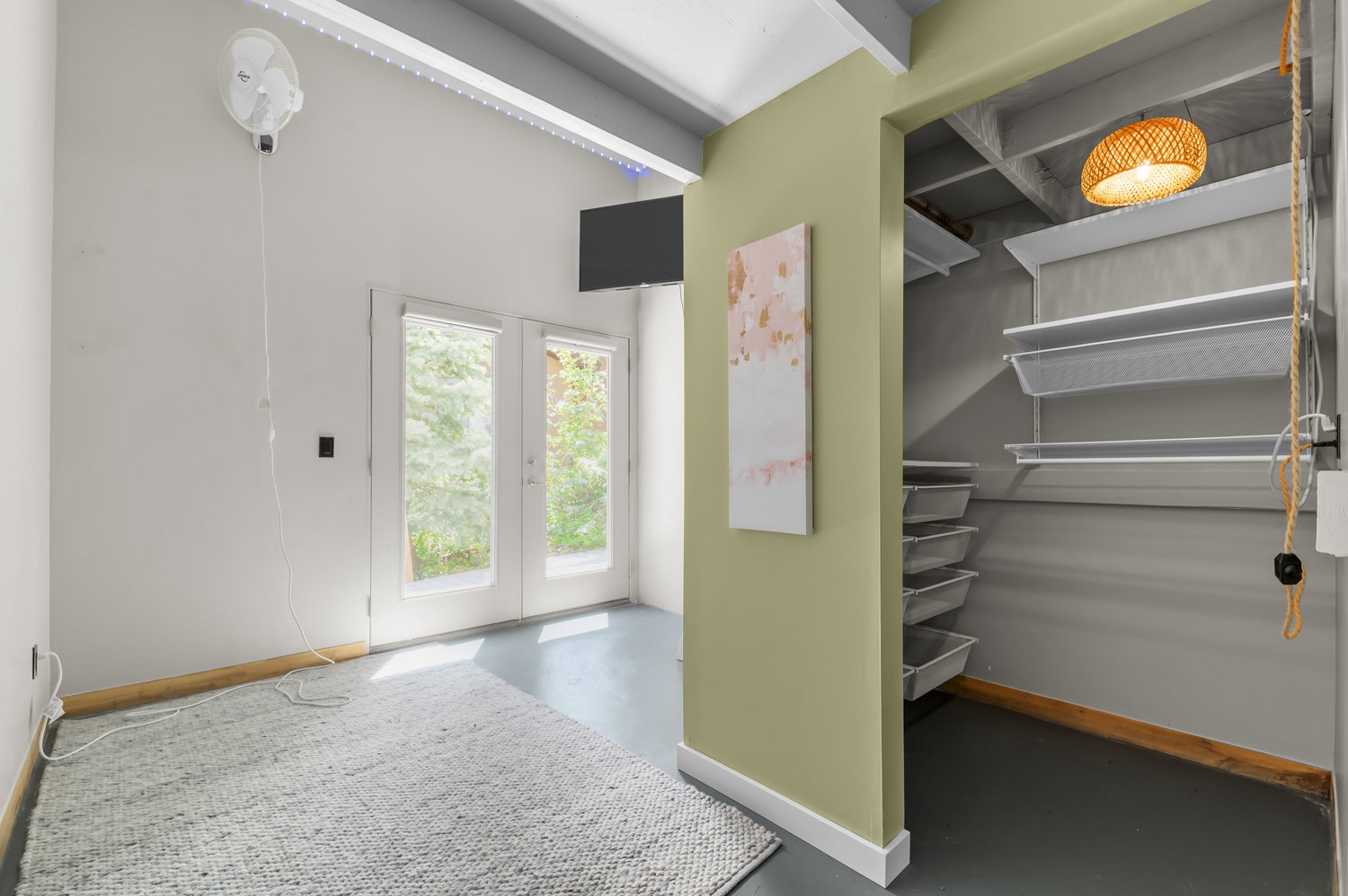 Room featuring light gray walls, exposed ceiling beams, and concrete flooring