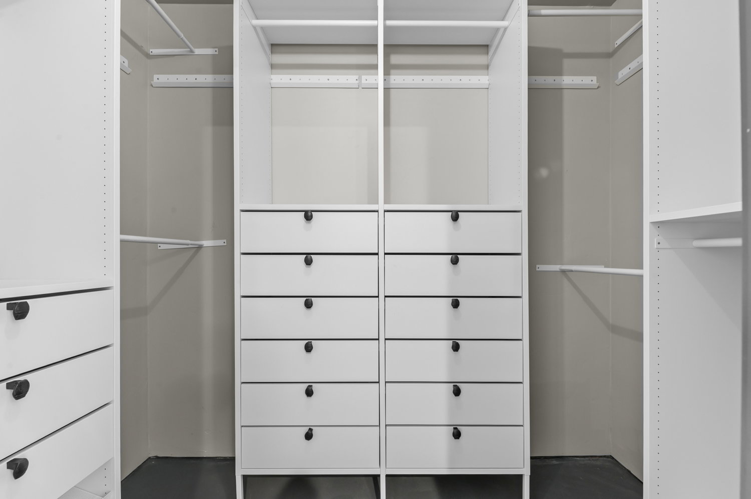 Custom closet system featuring multiple integrated drawer units with matte black hardware, adjustable shelving, and hanging rods