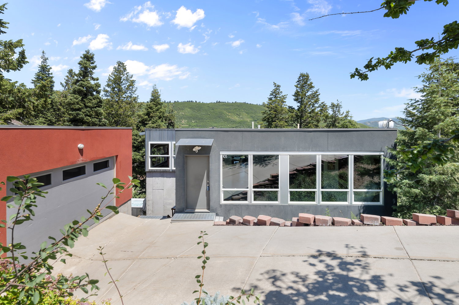 Modern exterior with a flat roofline, featuring large horizontal windows and a grey facade