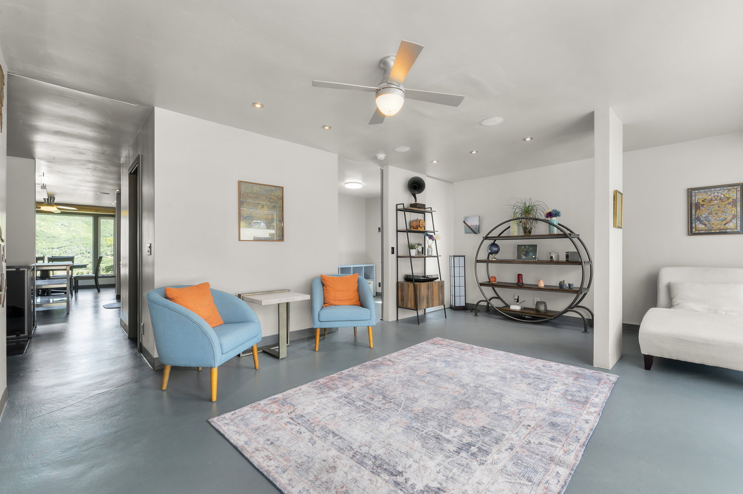 Expansive living area with light-toned flooring, recessed lighting, and a ceiling fan