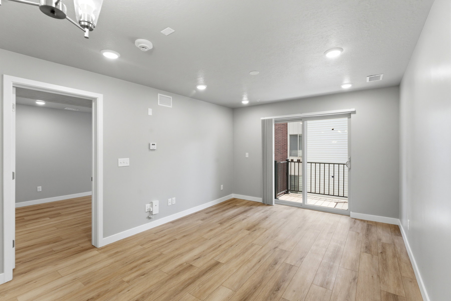 Spacious room featuring wood-finish flooring, light grey walls, recessed ceiling lighting, and white trim