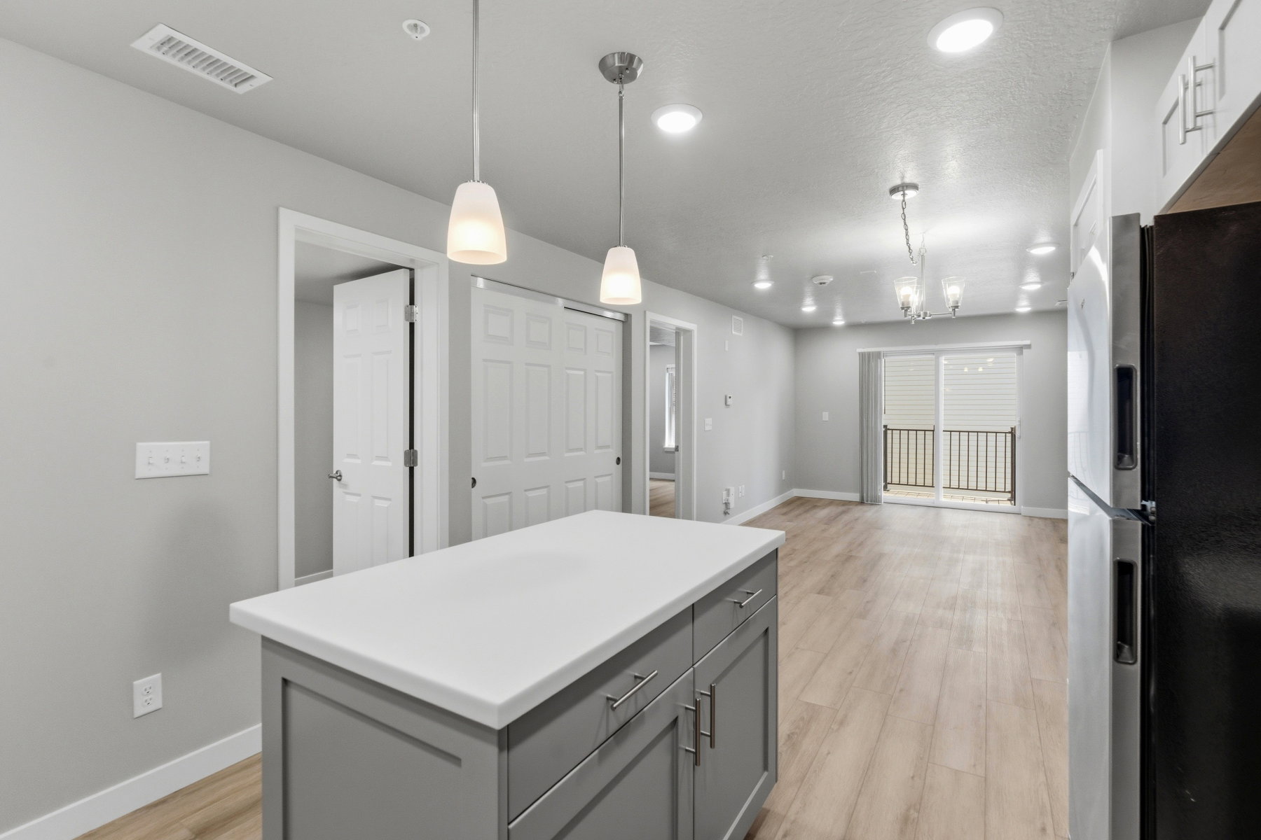 Kitchen island featuring a white countertop, pendant lighting, and gray cabinetry