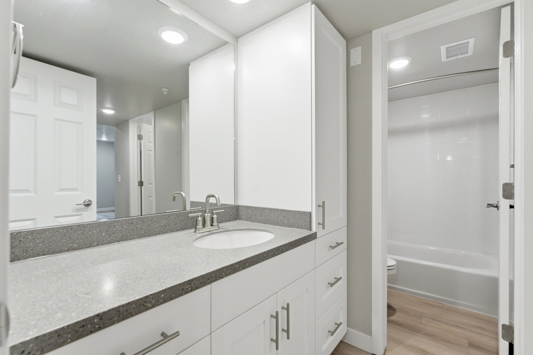 Bathroom vanity featuring a light gray speckled countertop, undermount sink, and brushed nickel faucet