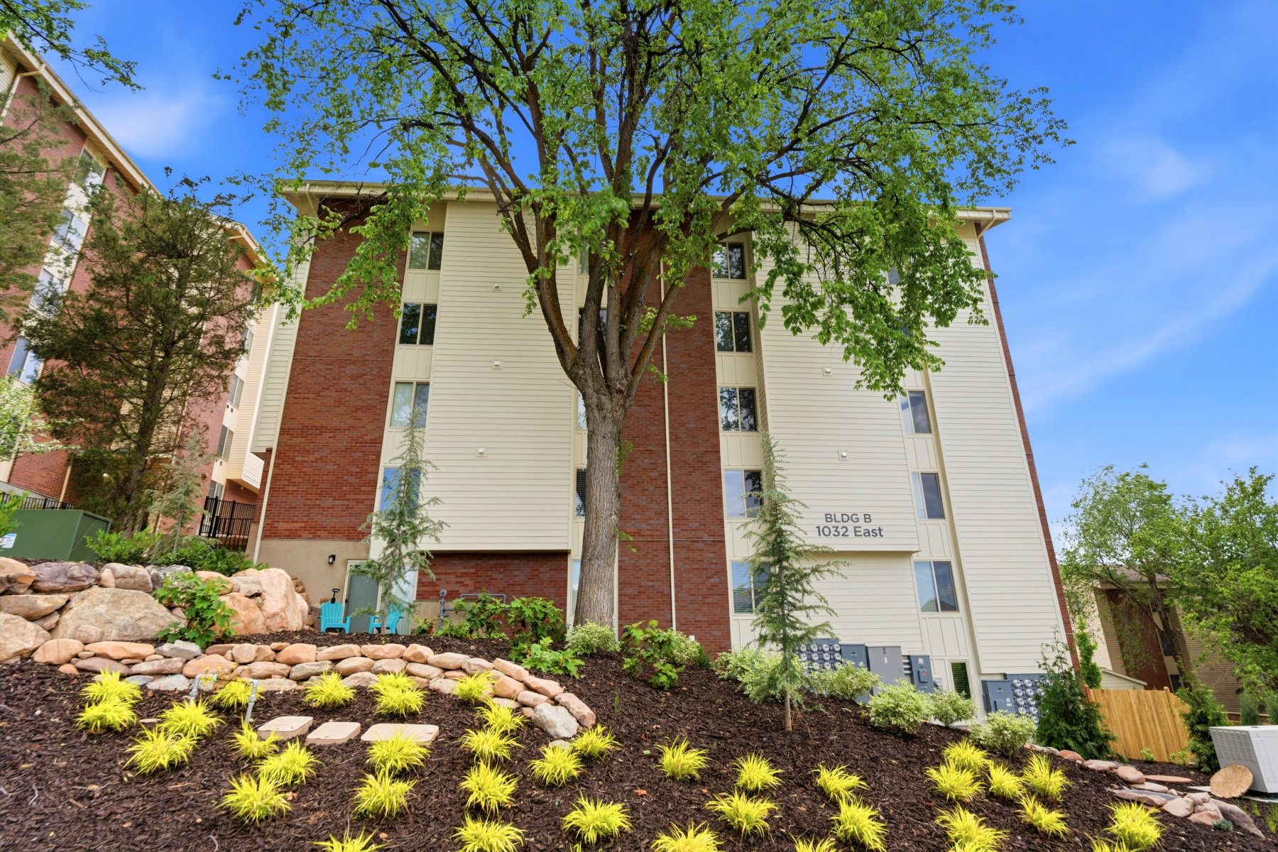 Multi-story building featuring tan siding and prominent brick accents