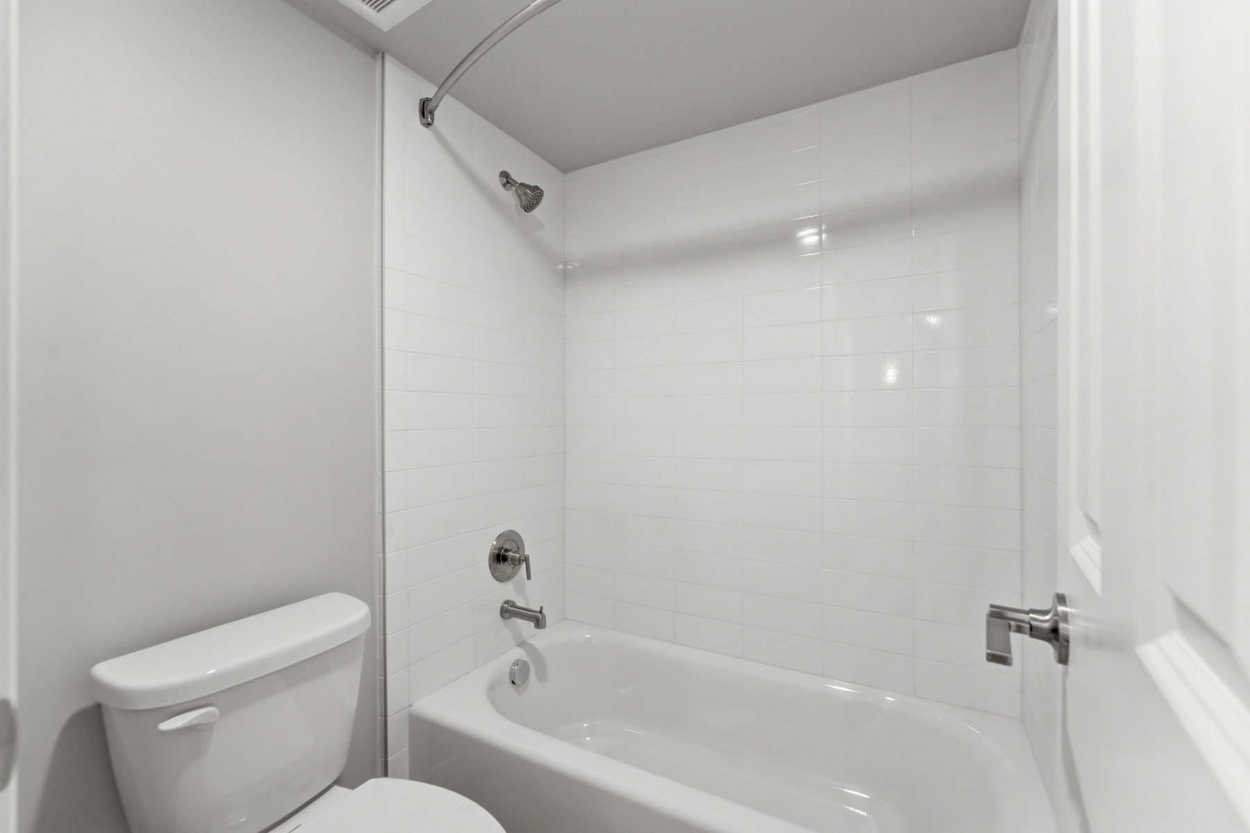 Full-size bathtub with a curved shower rod and brushed chrome fixtures