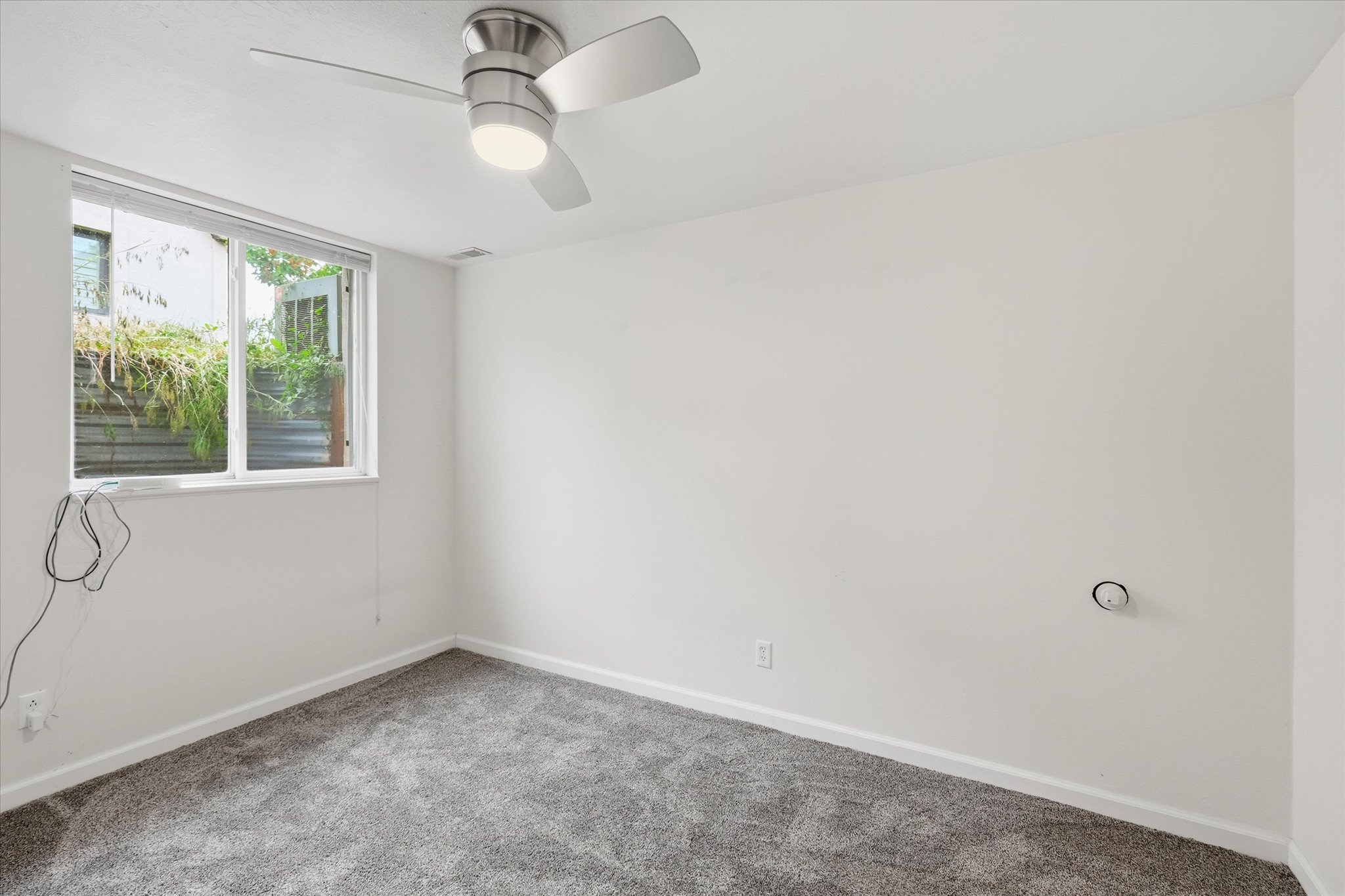 Room featuring a ceiling fan with integrated lighting, a double-pane window, and wall-to-wall carpeting