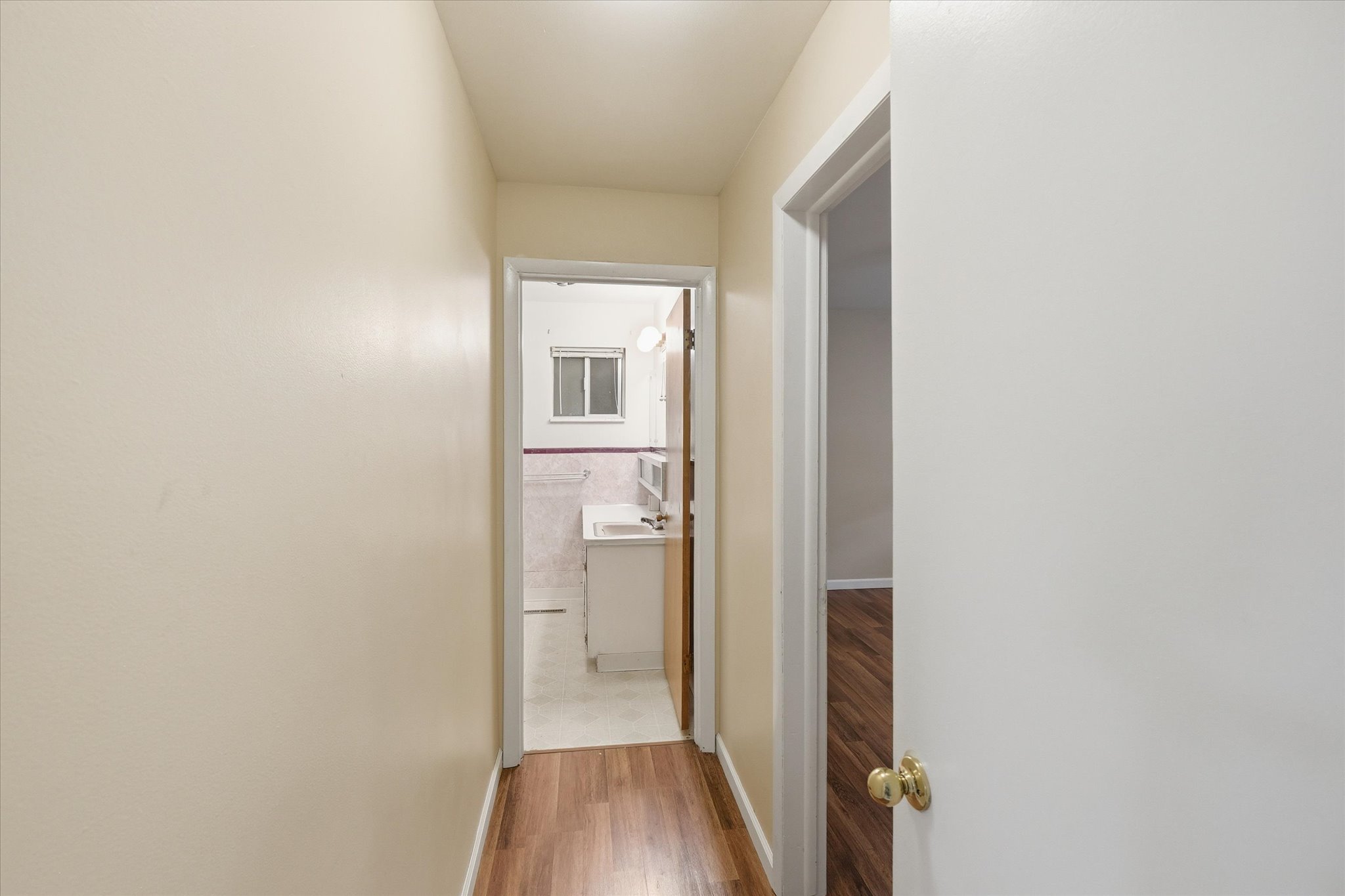 Hallway featuring wood-finish flooring, light-toned walls, and white trim