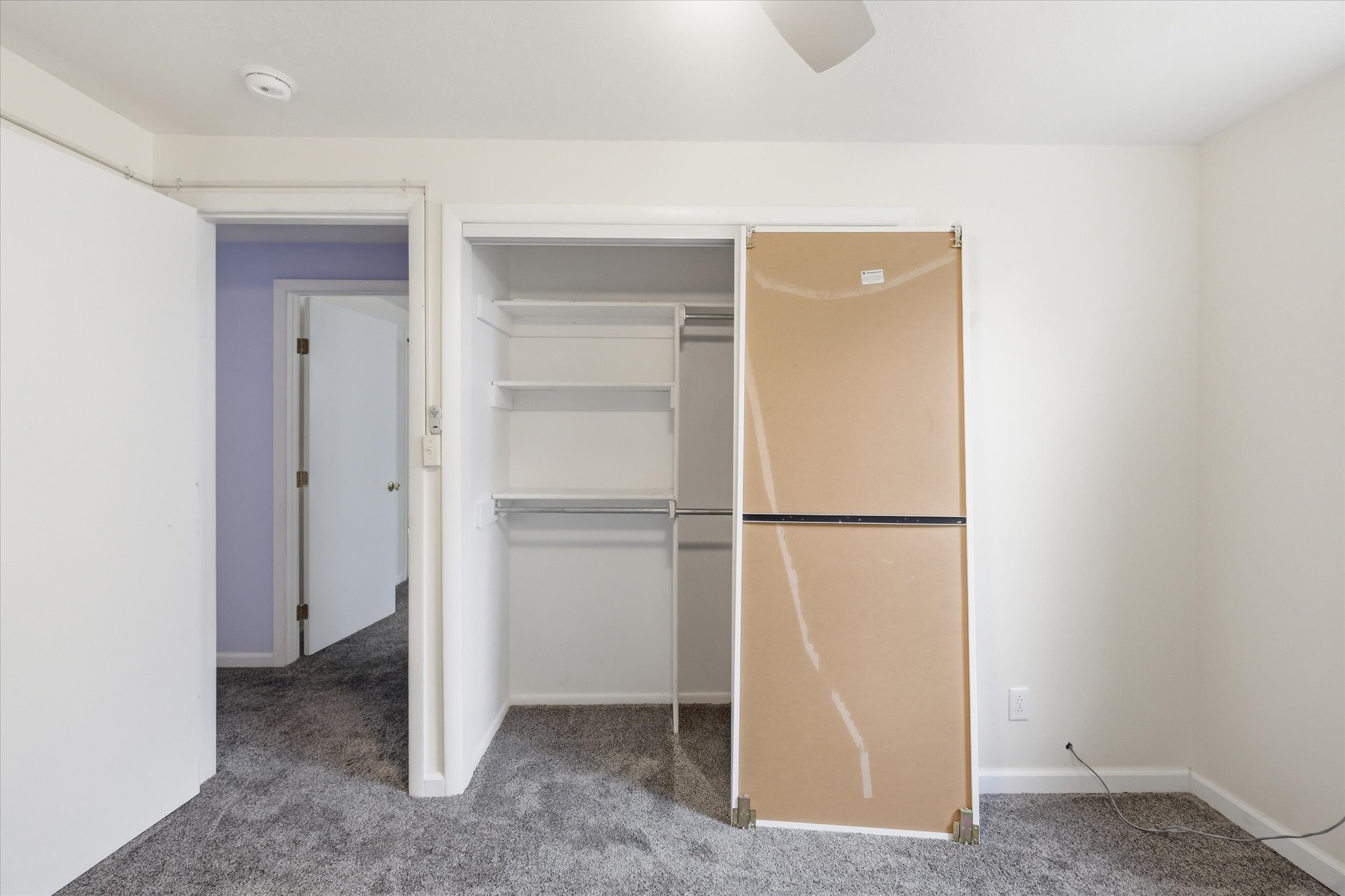 Bedroom featuring plush grey carpet, a ceiling fan, and a built-in closet with shelves and hanging rods