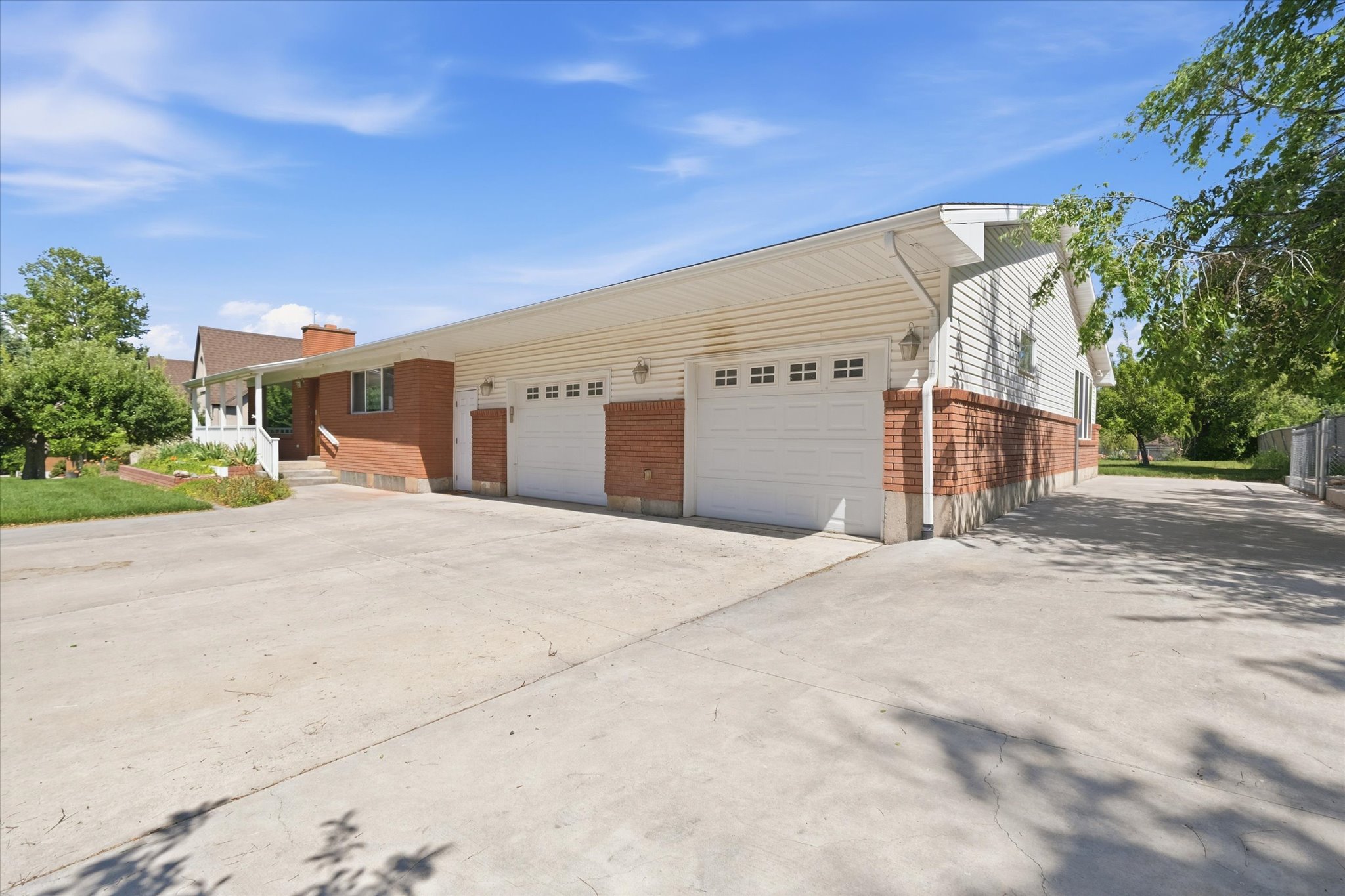 Two-car garage with white paneled doors and decorative windows, featuring brick accents and exterior lighting