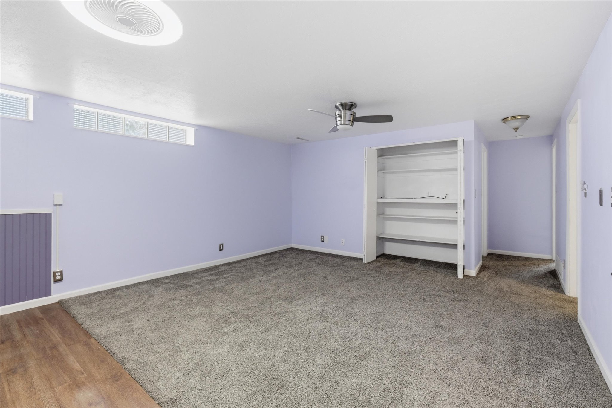 Spacious room featuring plush gray carpeting, recessed ceiling lighting, a ceiling fan, and built-in shelving