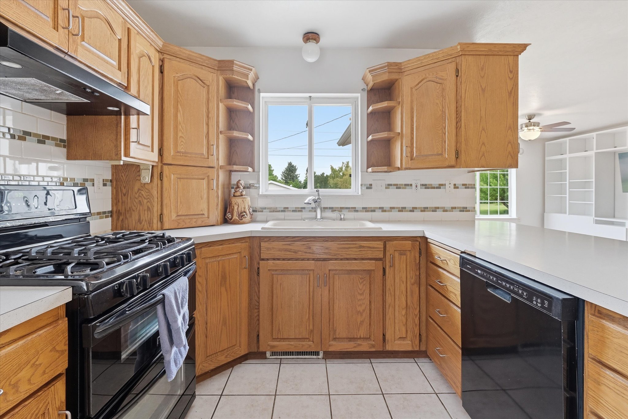 Kitchen featuring wood cabinetry, white countertops, tile flooring, a black gas range, and a black built-in dishwasher