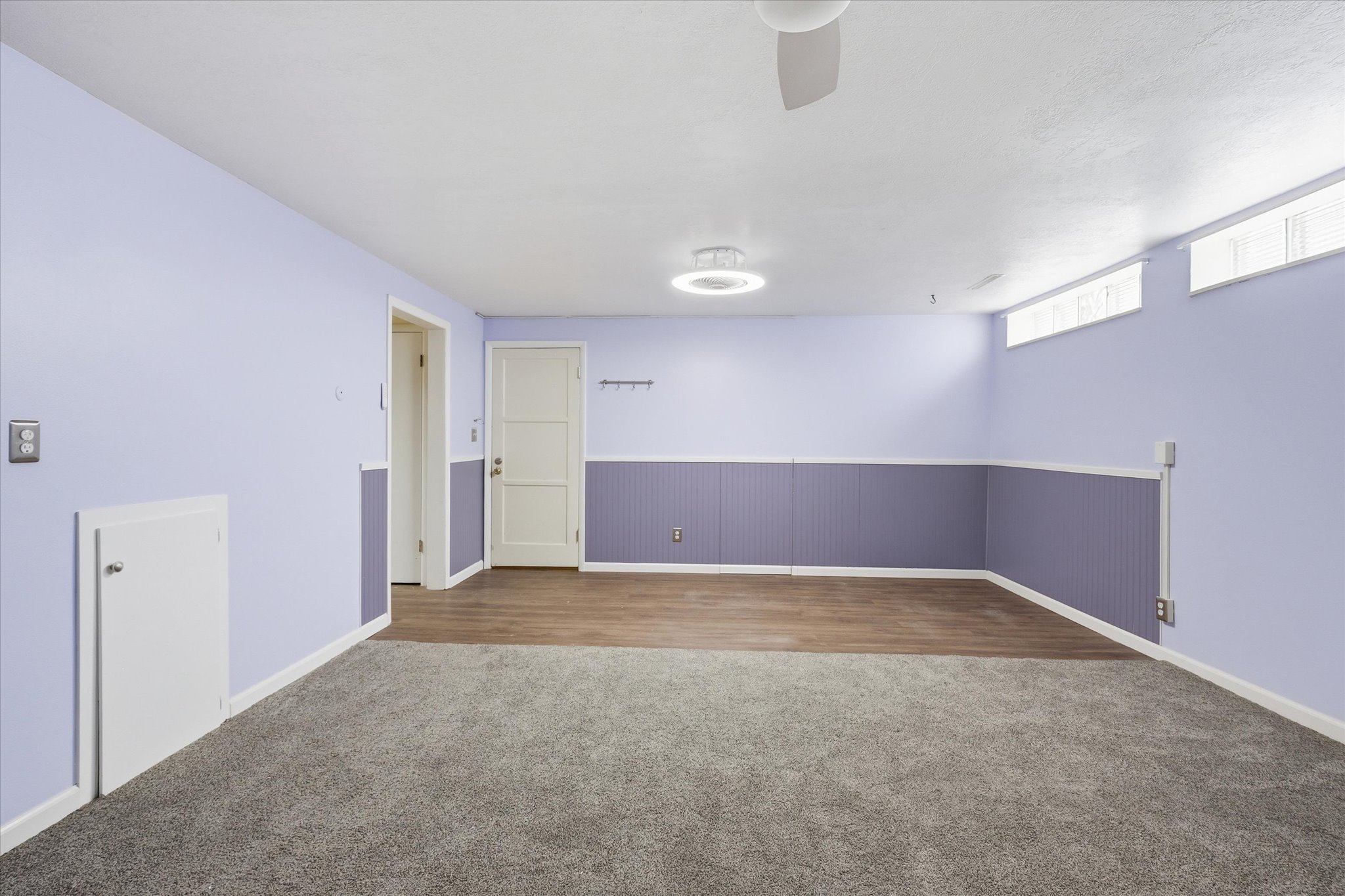 Spacious room featuring a combination of gray carpeting and wood-finish flooring