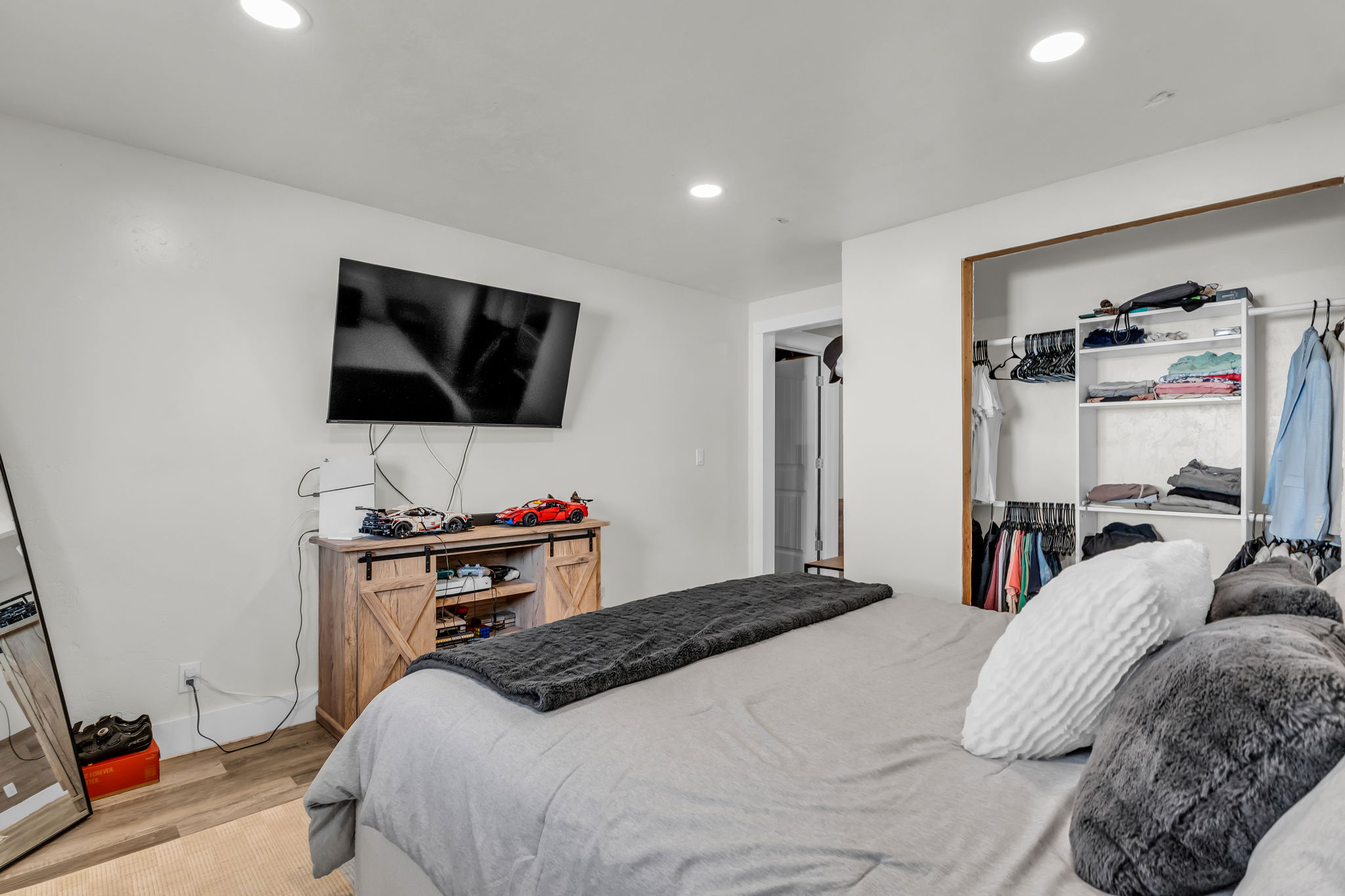 Spacious bedroom featuring recessed lighting, light wood-finish flooring, and a built-in closet with shelving and hanging rods