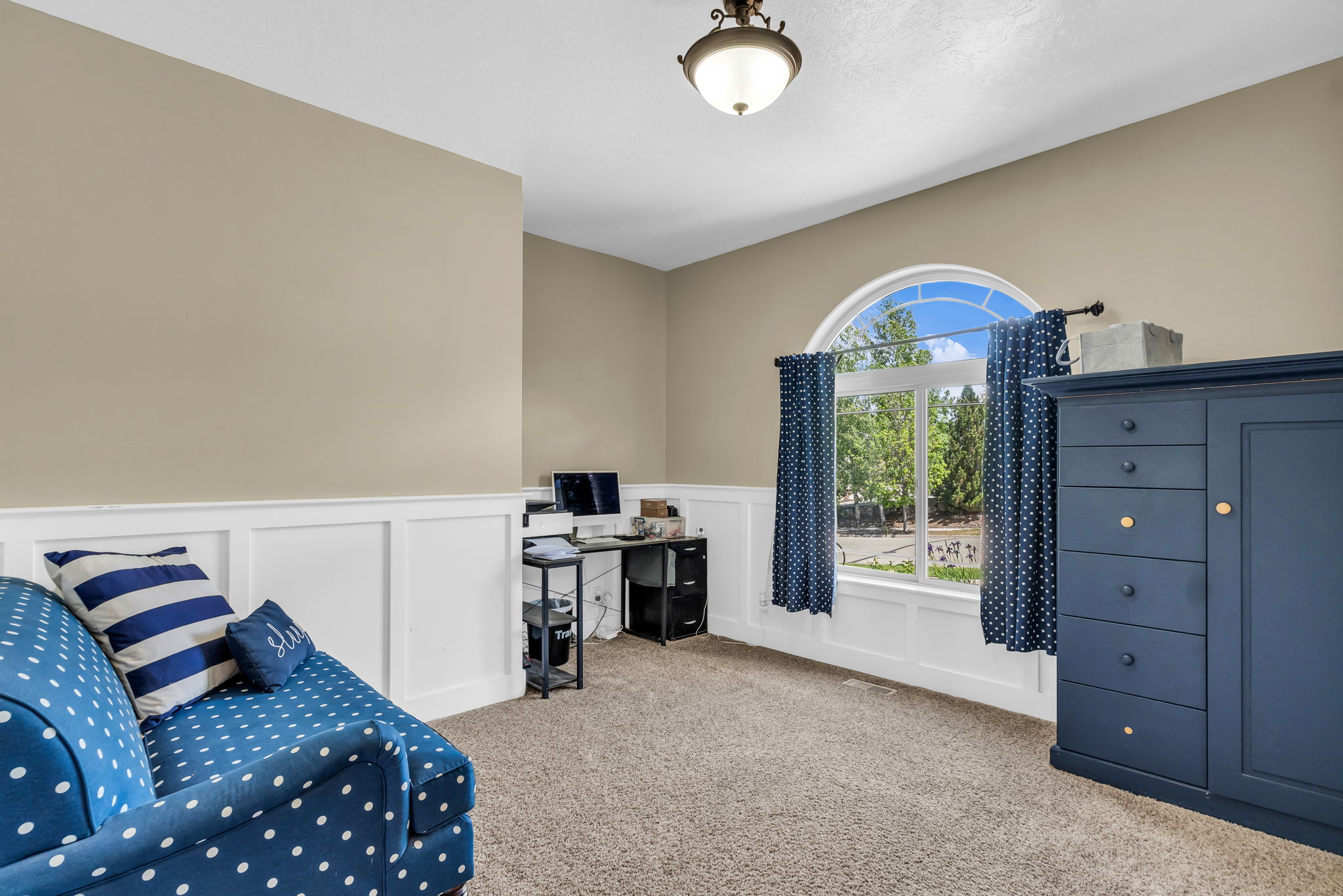 Carpeted room with a half-arch window, white wainscoting, and a ceiling-mounted light fixture