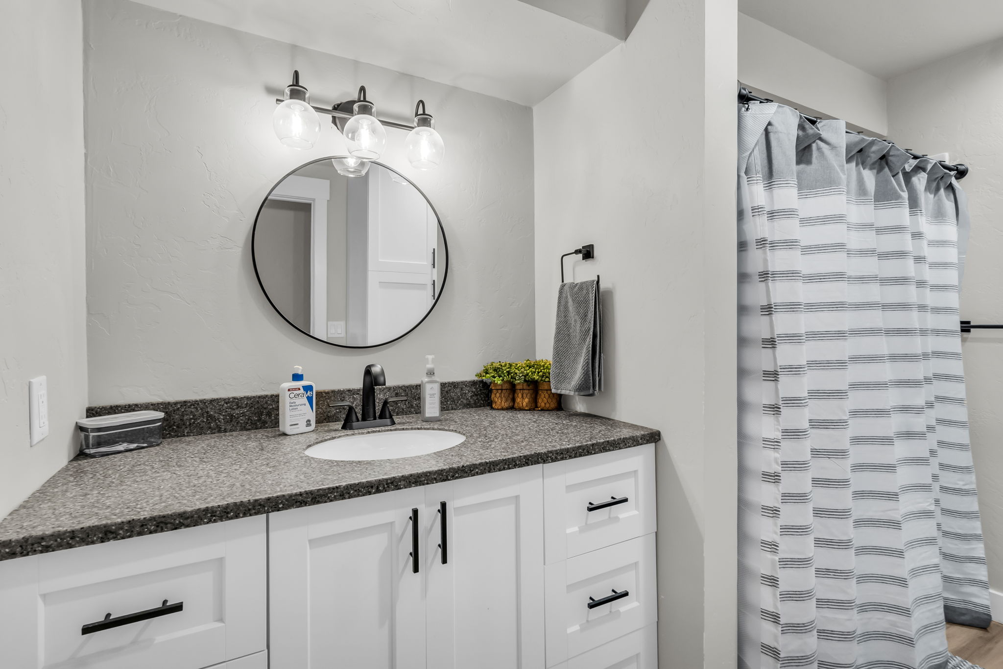 Bathroom vanity featuring a dark speckled countertop with an undermount sink and matte black faucet