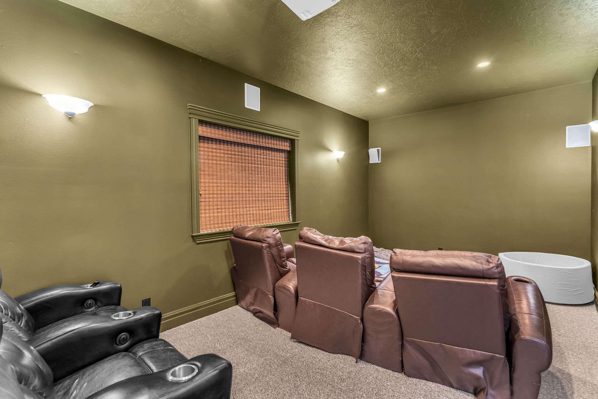 Dedicated media room featuring recessed lighting, wall sconces, and built-in wall speakers