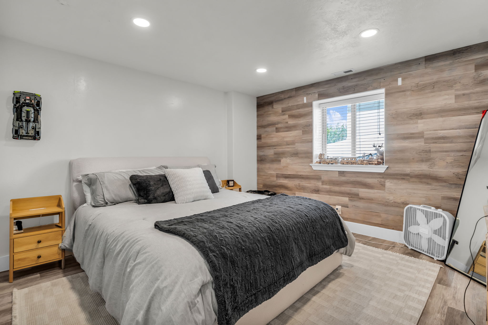 Bedroom featuring a wood-finish accent wall with a window, recessed ceiling lighting, and wood-look flooring