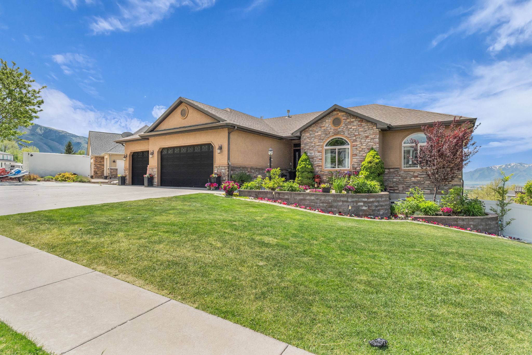 Stucco exterior featuring stone accents, a multi-car garage, and arched windows