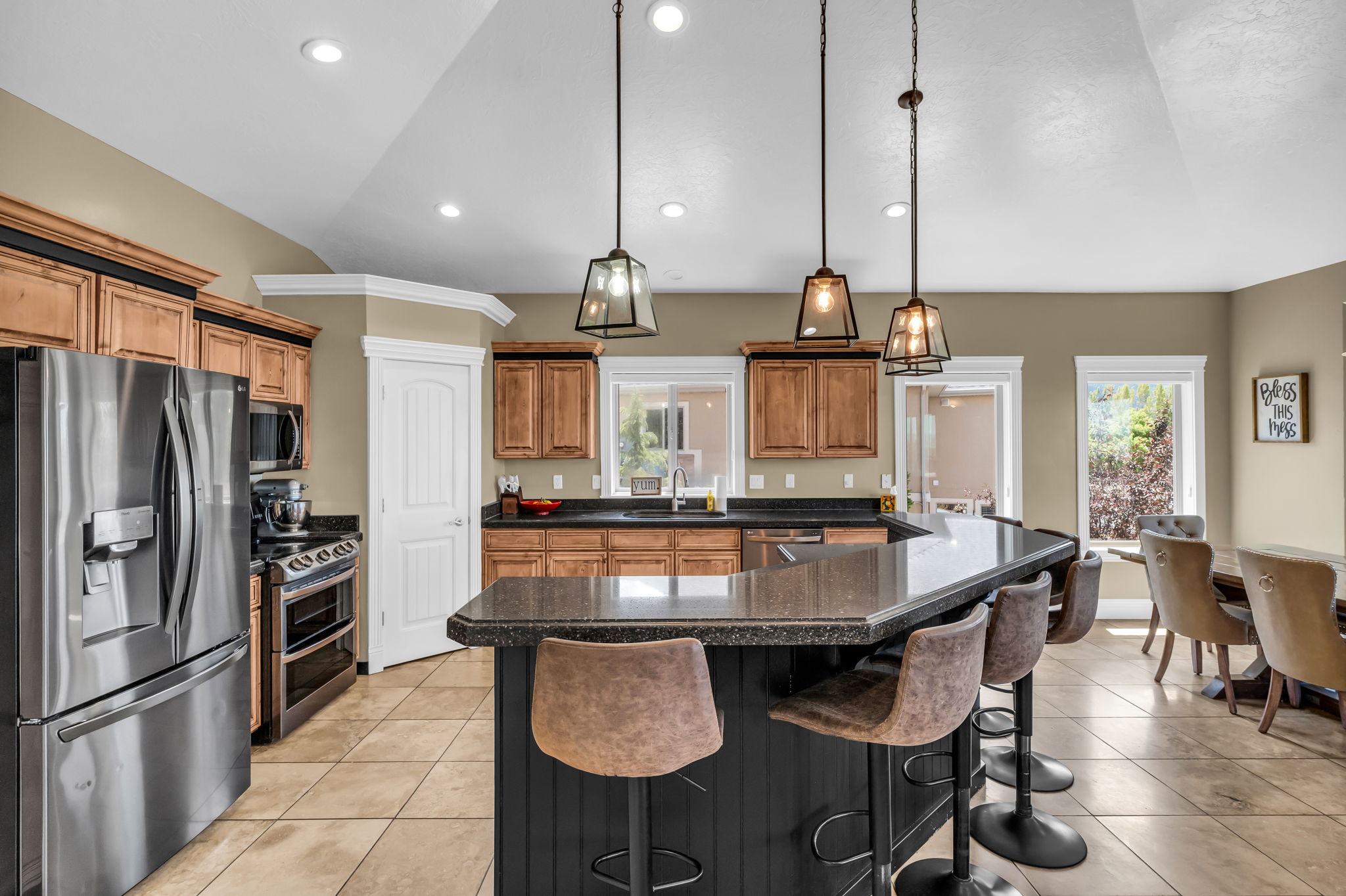 Kitchen featuring a dark-toned breakfast bar, pendant lighting, stainless steel appliances, light wood-finish cabinetry, and tile flooring