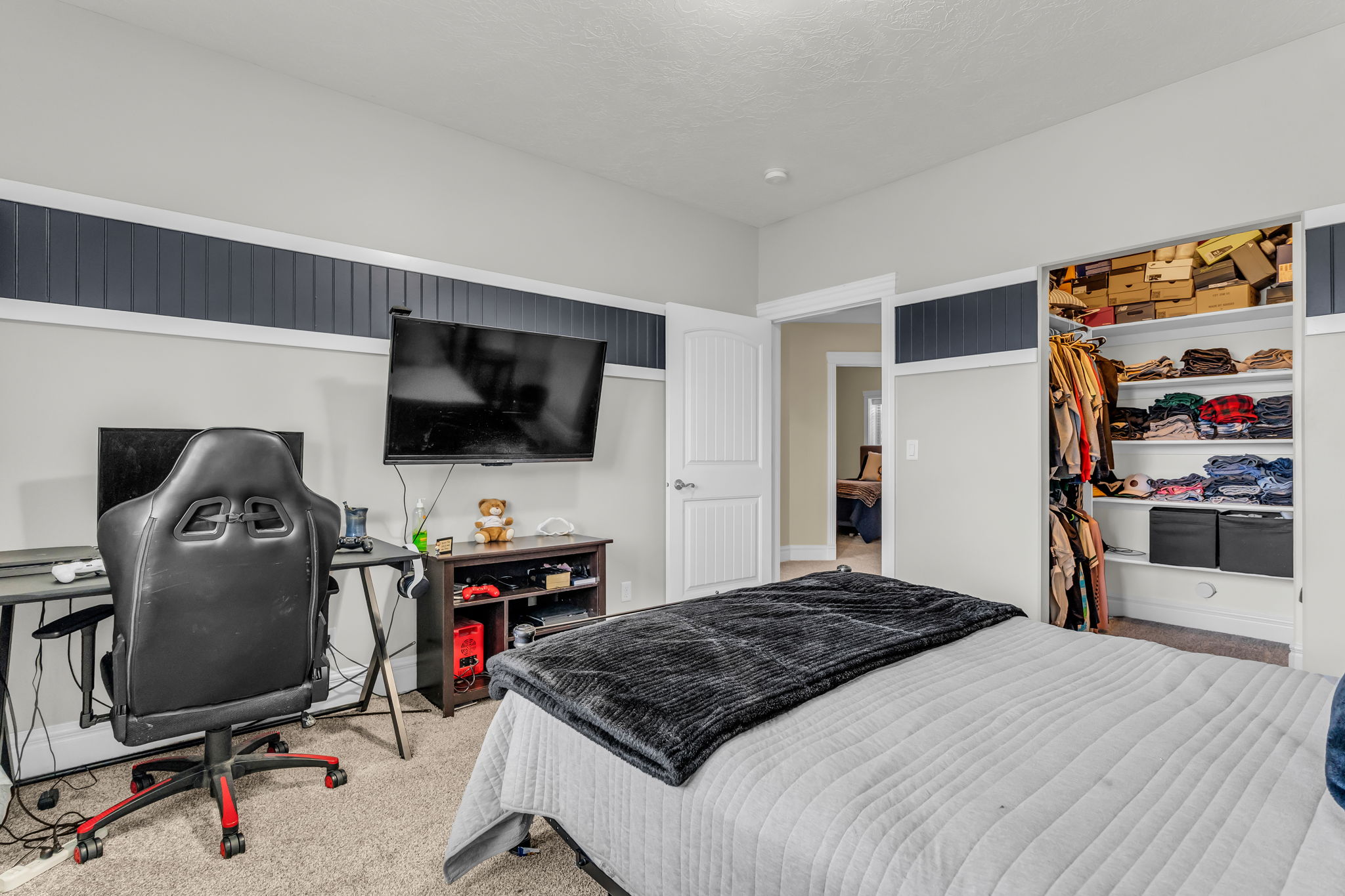 Carpeted room featuring a white interior door, a built-in closet with shelving, and wainscoting accent walls