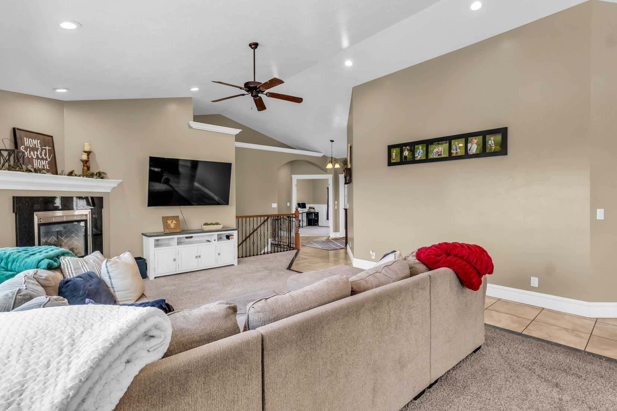 Spacious living area featuring a fireplace with a mantel, vaulted ceilings, recessed lighting, and a ceiling fan