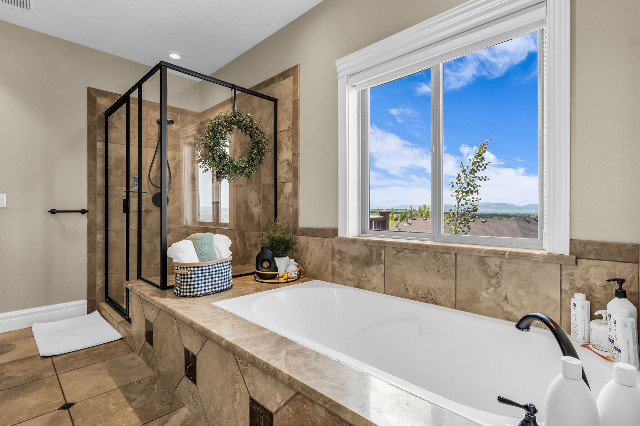 Soaking tub with a matte black faucet, surrounded by natural stone tiling