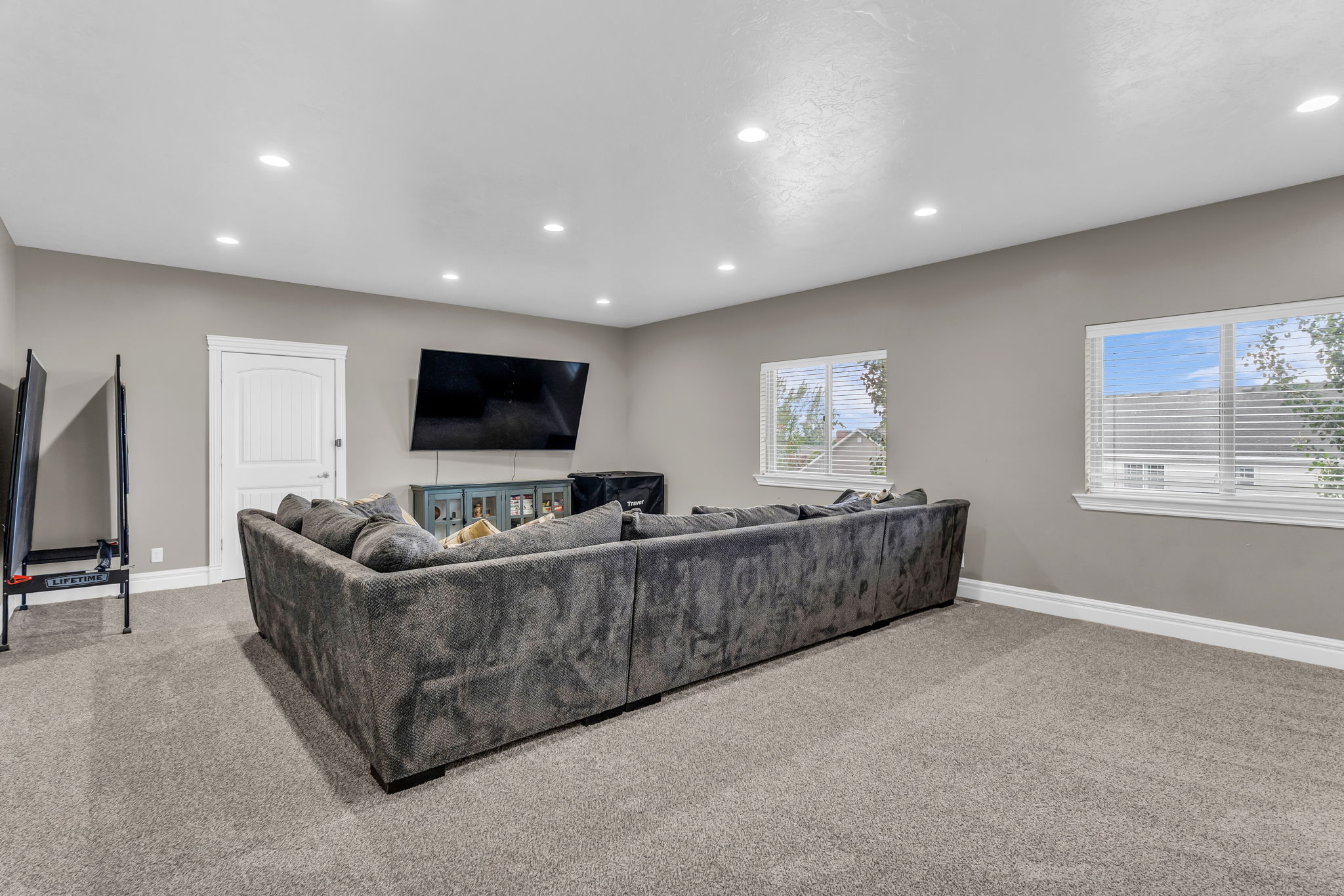Spacious carpeted room featuring recessed lighting and two windows with blinds