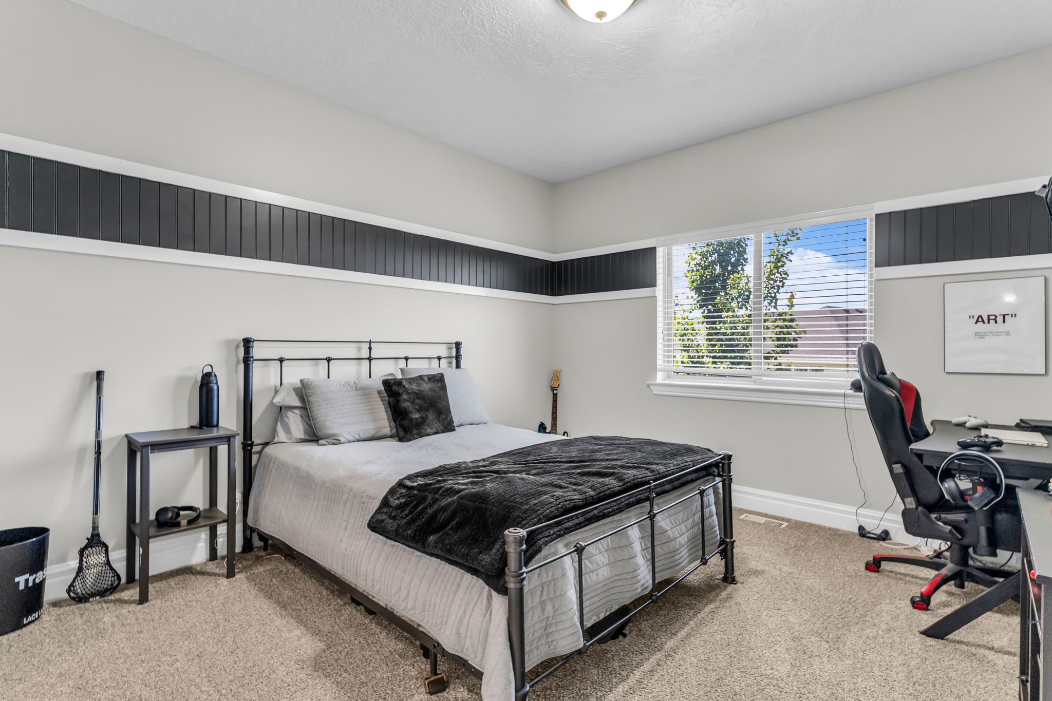 Windowed room featuring textured carpeting, a single window with blinds, and a built-in trim accent band with vertical paneling