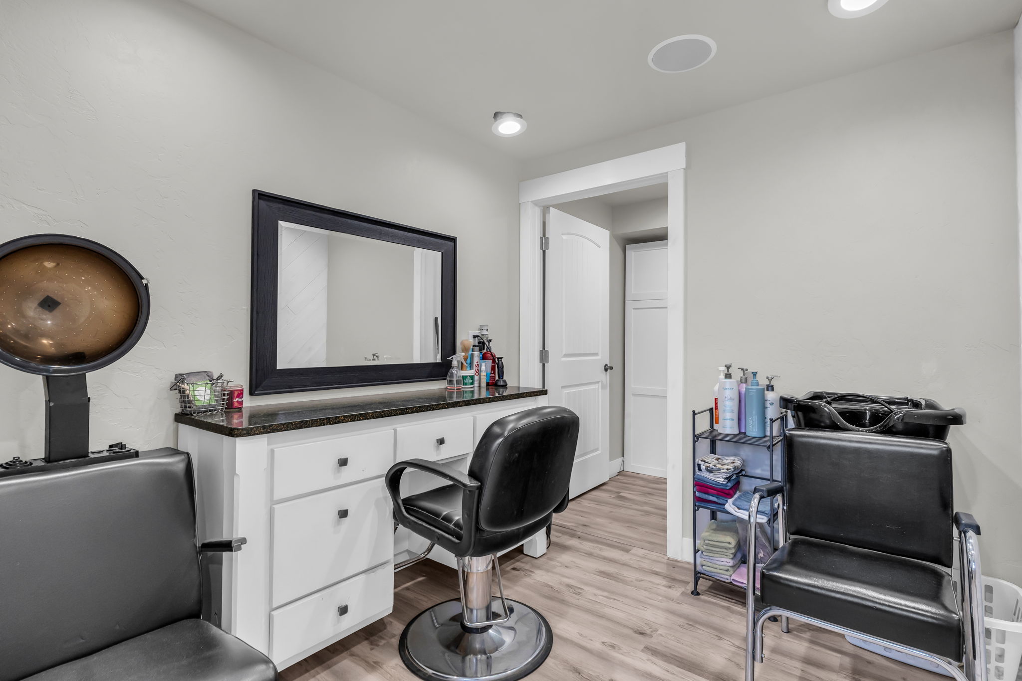Dedicated room featuring wood-finish flooring, white cabinetry with dark pulls, and a dark countertop